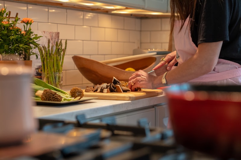 Someone prepping vegetables on a cutting board at a kitchen counter.